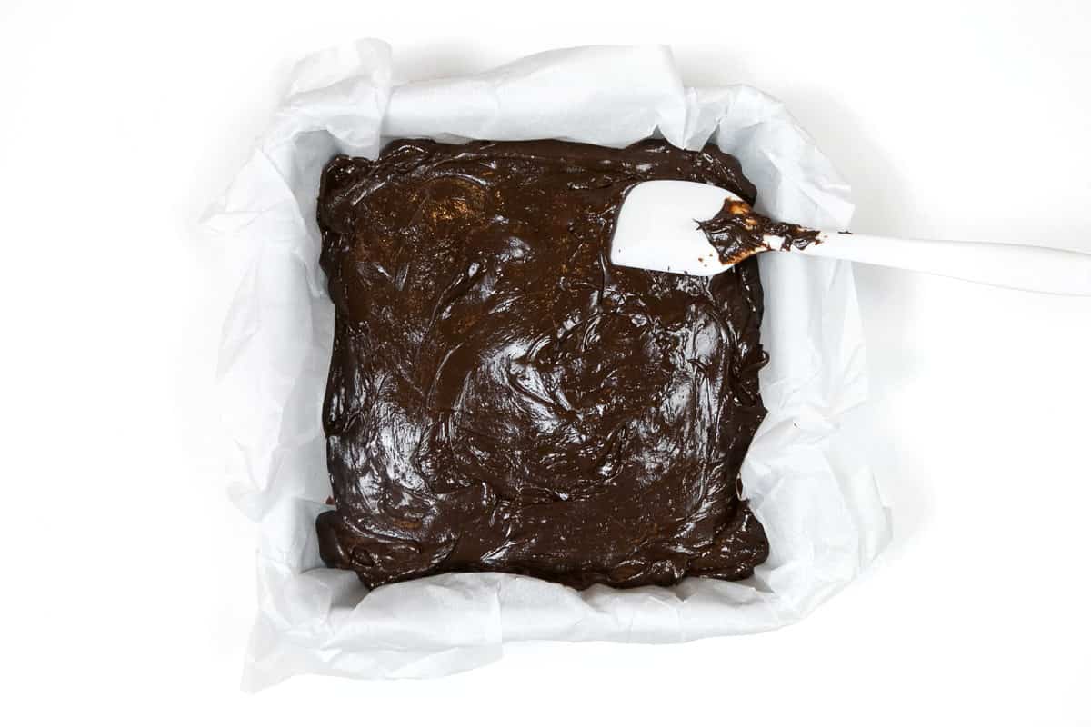 The fudge mixture is poured into a pan with parchment paper.