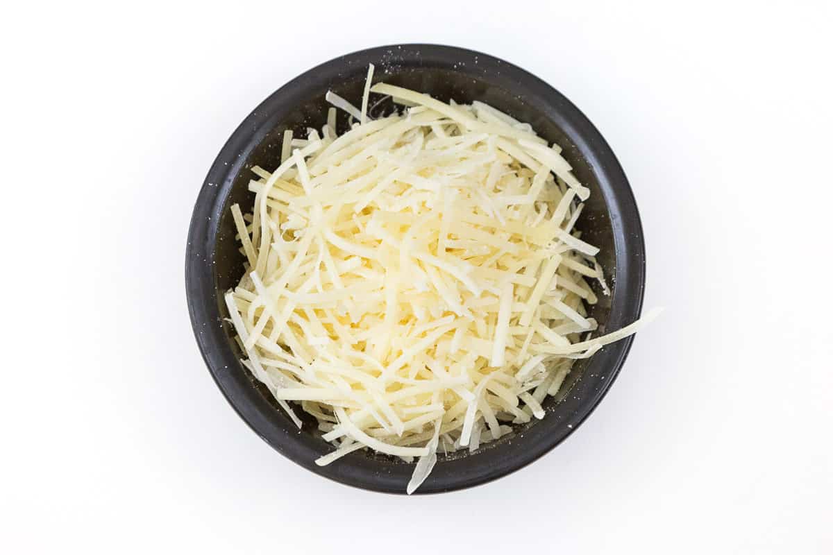 A half of a cup of shredded Parmesan cheese in a bowl.